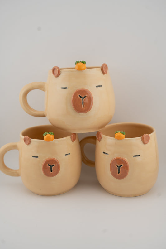 Three beige ceramic mugs with bear faces on a light gray background