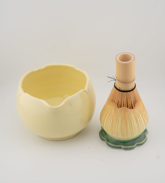 Yellow ceramic whisk holder and wooden whisk on a light gray background