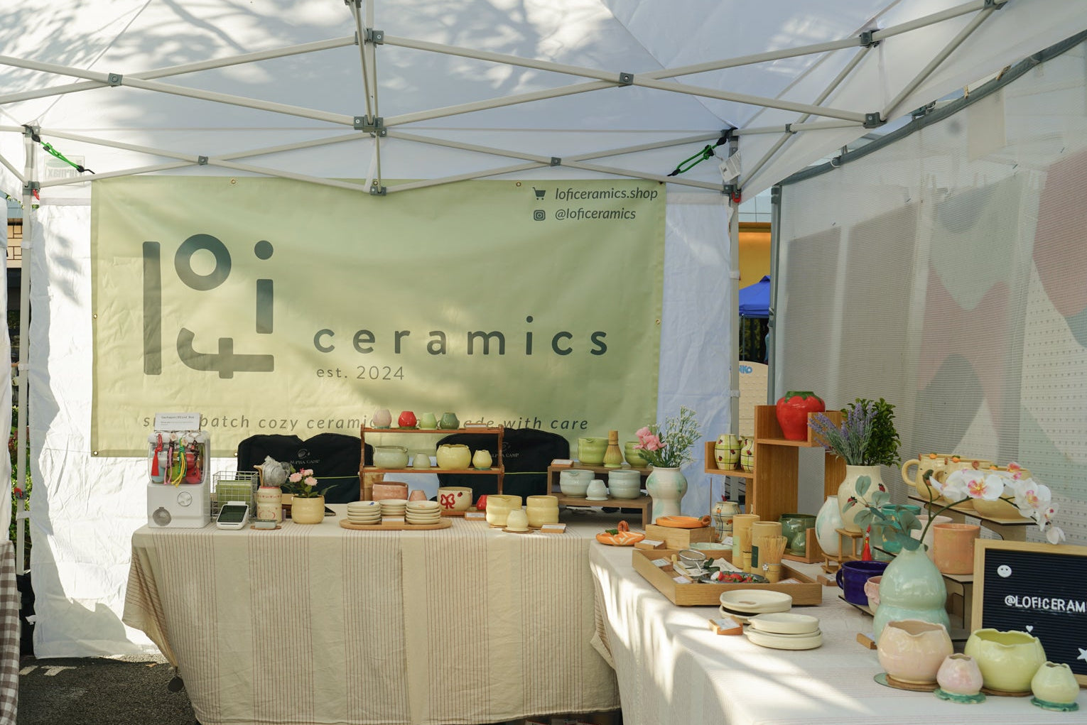 Ceramics booth with various items under a tent at an outdoor event.